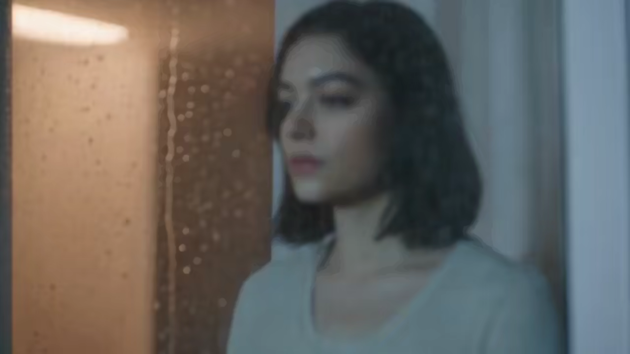 Cinematic woman beside a rain-fogged window at night